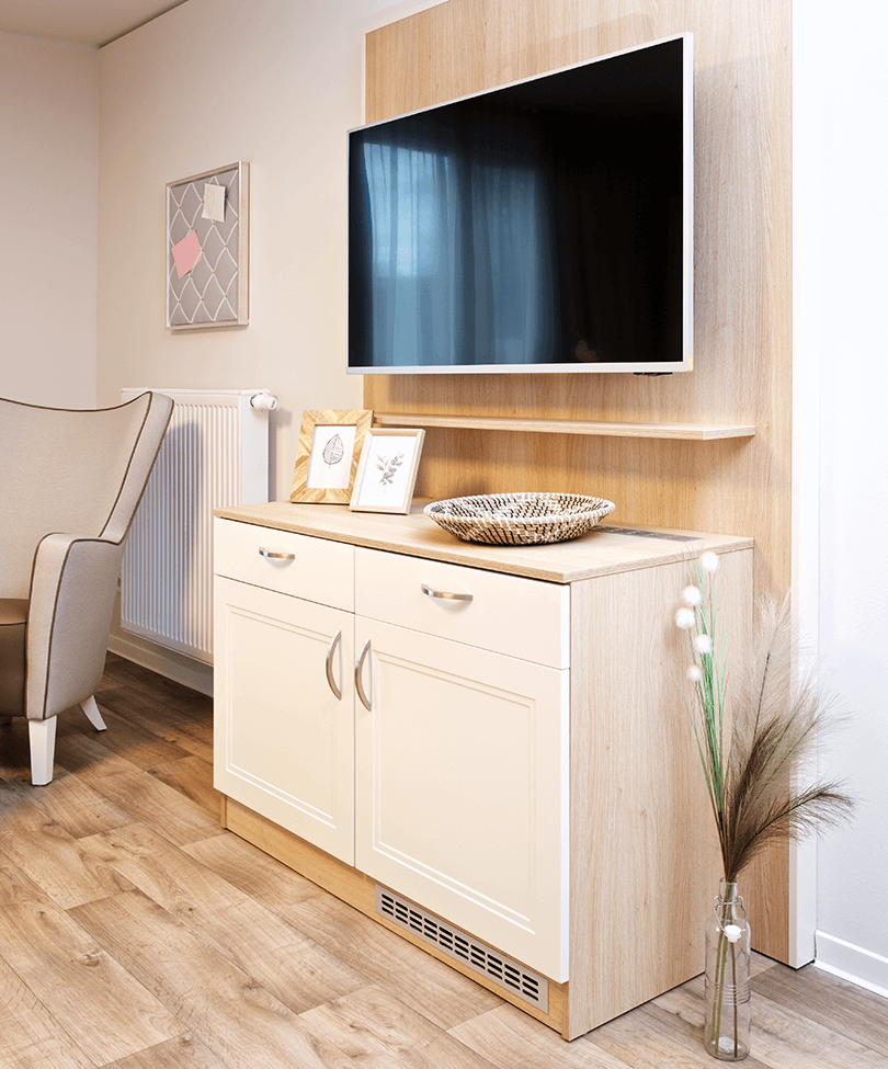 Kommode unter einem TV in einem Bewohnerzimmer