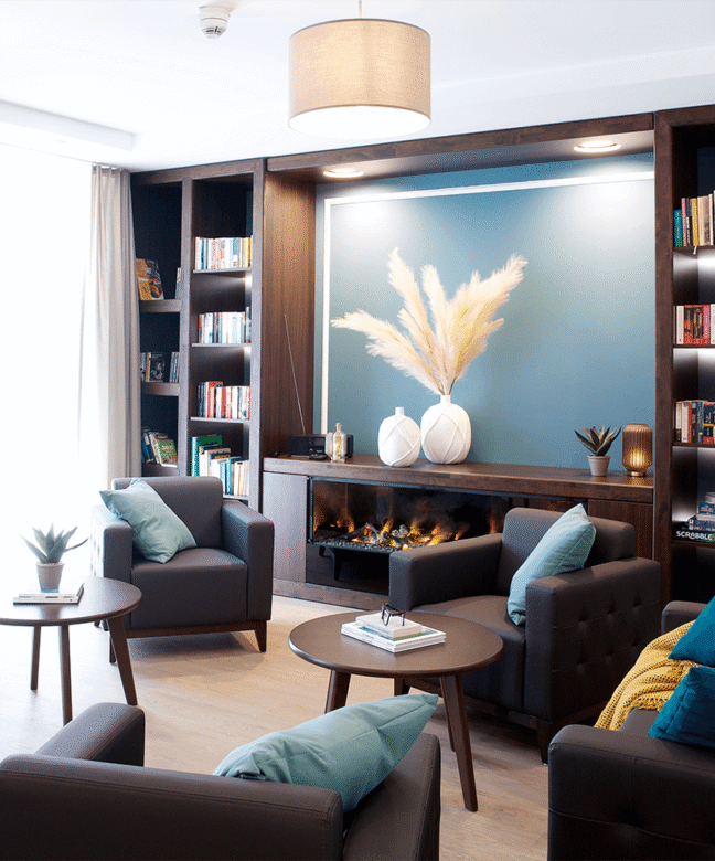 Gemeinschaftsraum mit Dekoelementen und Wandfarben in Blau mit einem Wandregal und Sitzmöglichkeiten