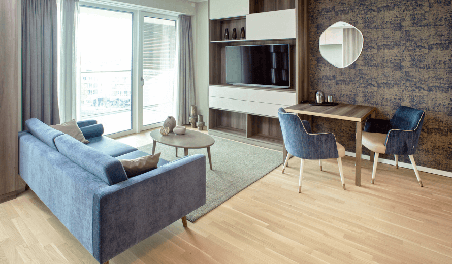 Mikroapartment mit einem TV Wandschrank und einem Wohnzimmerbereich mit einem blauen Sofa.