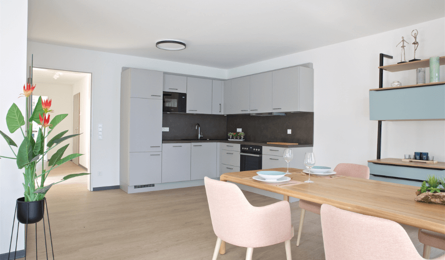 Objekteinrichtung vom Betreuten Wohnen mit einer modernen und barrierefreien Wohnung mit einer Küche und Tisch und Stühlen.