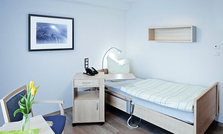 Pflegebett und Nachtschrank in einem Patientenzimmer einer Rehaeinrichtung