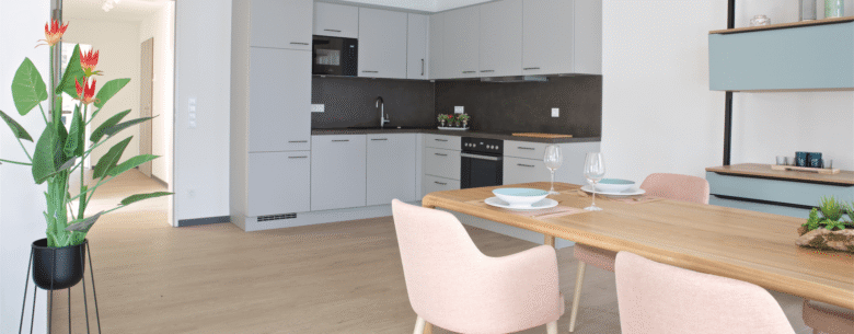 Objekteinrichtung vom Betreuten Wohnen mit einer modernen und barrierefreien Wohnung mit einer Küche, Tisch und Stühlen.