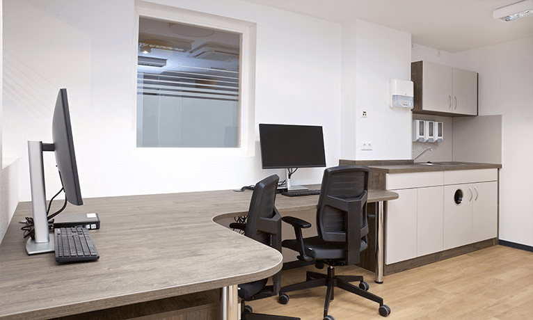 Schwarzer ergonomischer Bürostuhl mit einem Eckschreibtisch in einem Dienstzimmer einer Pflegeeinrichtung