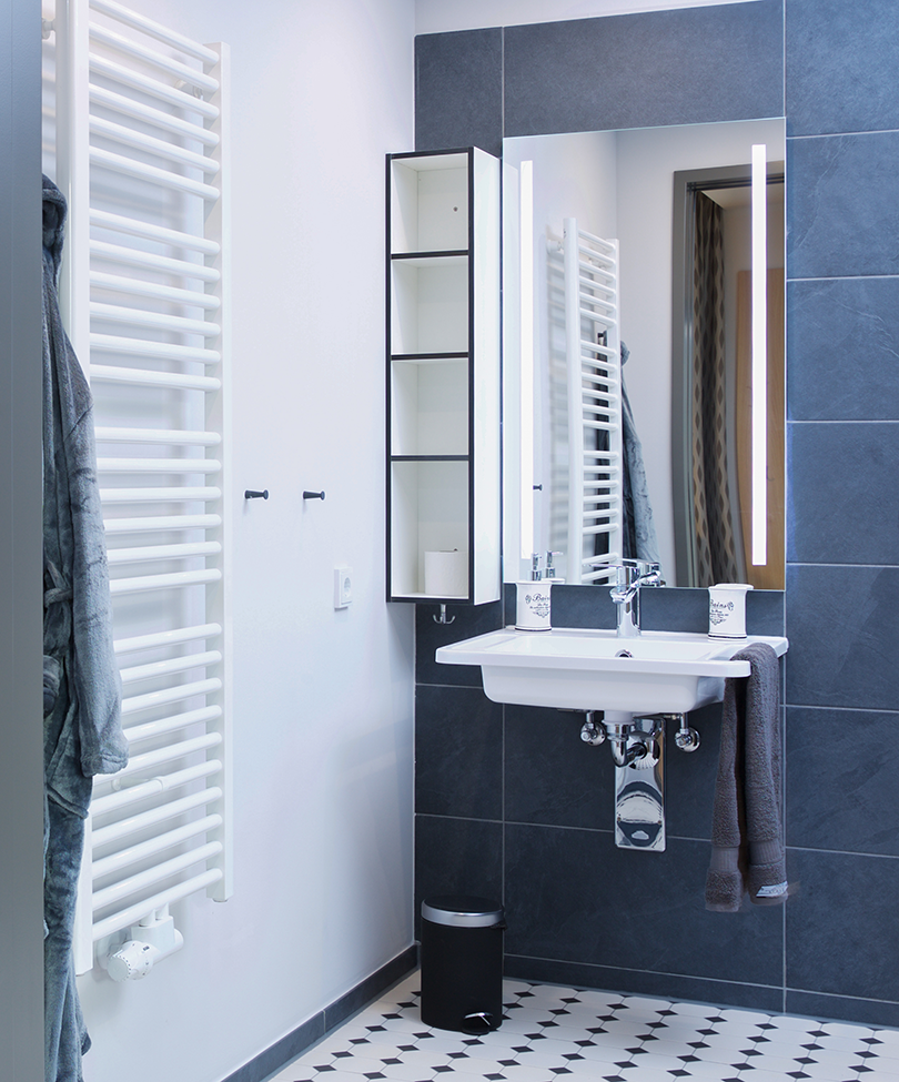 Pflegebad miz Handtuchheizung, Waschbecken und Spiegelschrank.