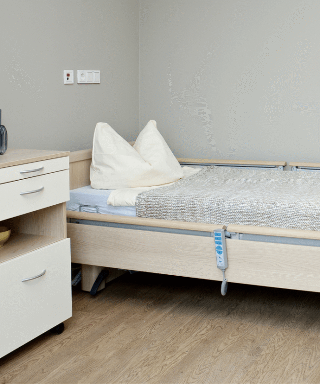 Bett und Nachtschrank in einem Bewohnerzimmer.