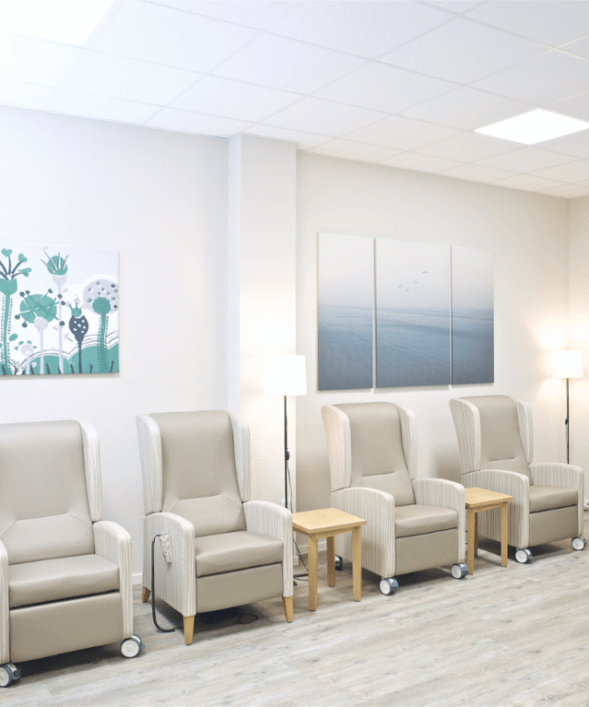 Therapieraum einer Pflegeeinrichtung mit weissen Ruhesesseln in weiss grau an einer Wand stehend.