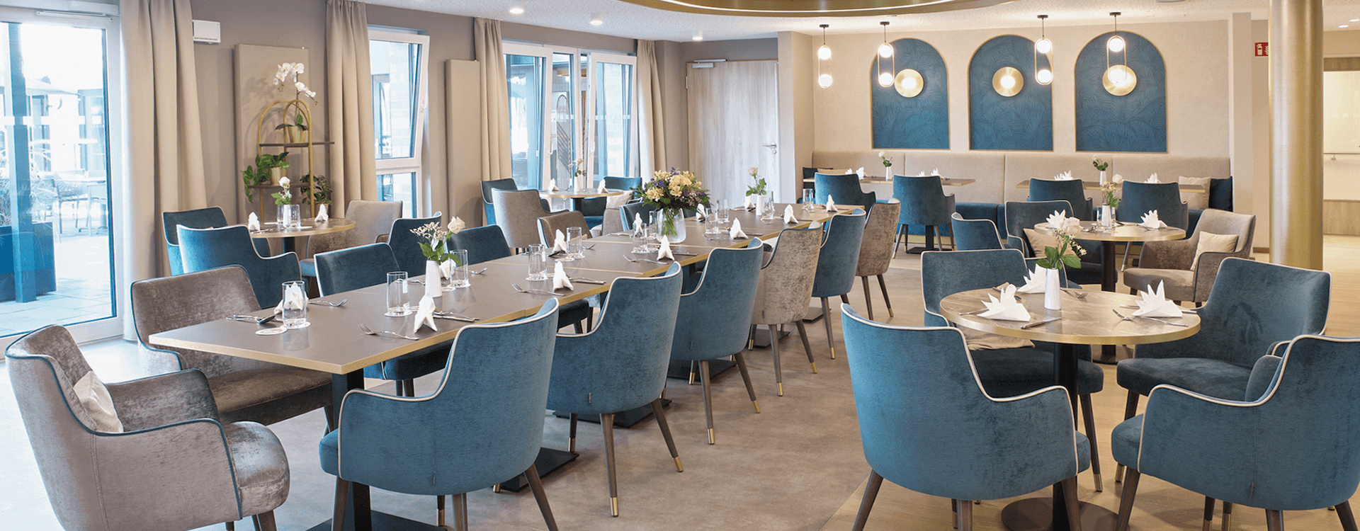 Stilvolles Raumkonzept mit blauen Stühlen und Holztischen und einer hellen und natürlichen Beleuchtung in einem Restaurantbereiche