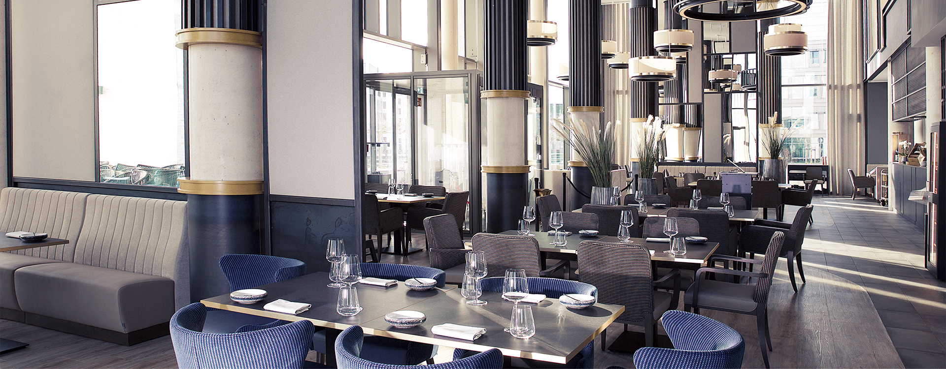 Großer Restaurant Bereich mit großen lichtdurchfluteten Fenstern und moderner Bestuhlung in Lila und Akzenten in grau.